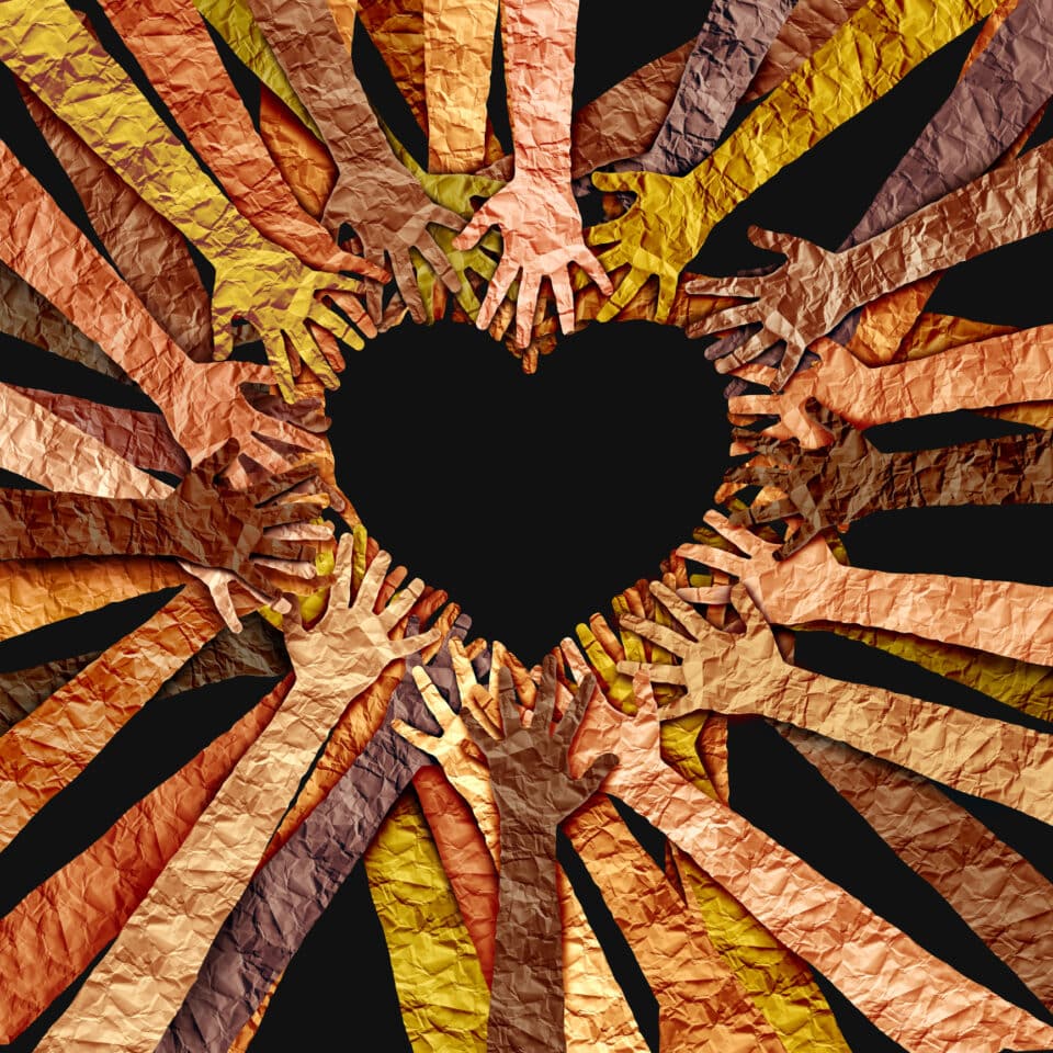 Heart shaped art piece formed with paper cutouts of human arms and hands meant to represent diversity.