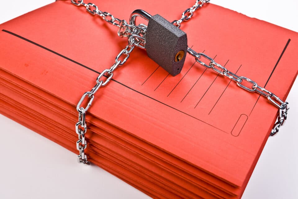 Stack of red files encased in chains and a lock.